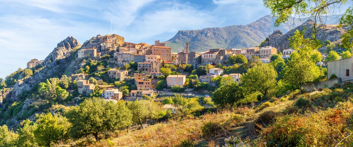 A mountainous village with buildings nestled among rocky terrain and trees.