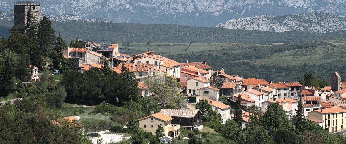 A mountainous village with terracotta-roofed buildings and a prominent tower.