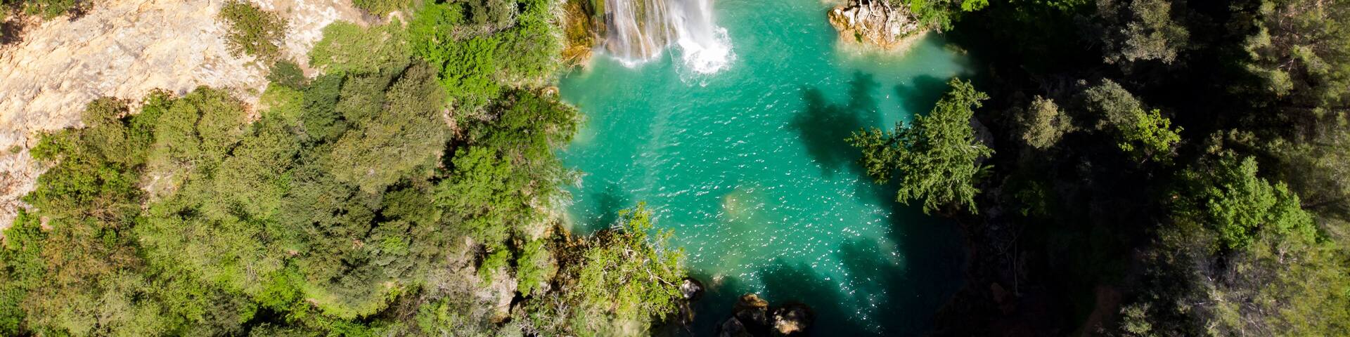 A waterfall cascading into a turquoise pool surrounded by dense forest.
