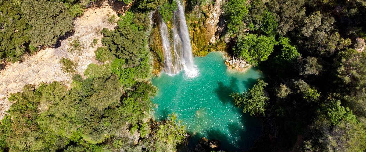 A waterfall cascading into a turquoise pool surrounded by dense forest.