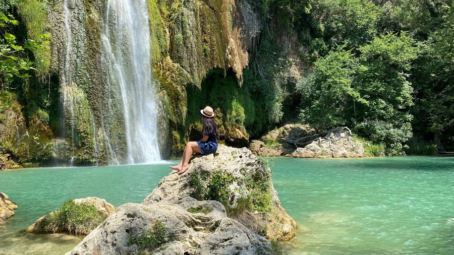 Une cascade se jetant dans un bassin d’eau turquoise et limpide, entouré d’un paysage rocheux et d’une végétation luxuriante.