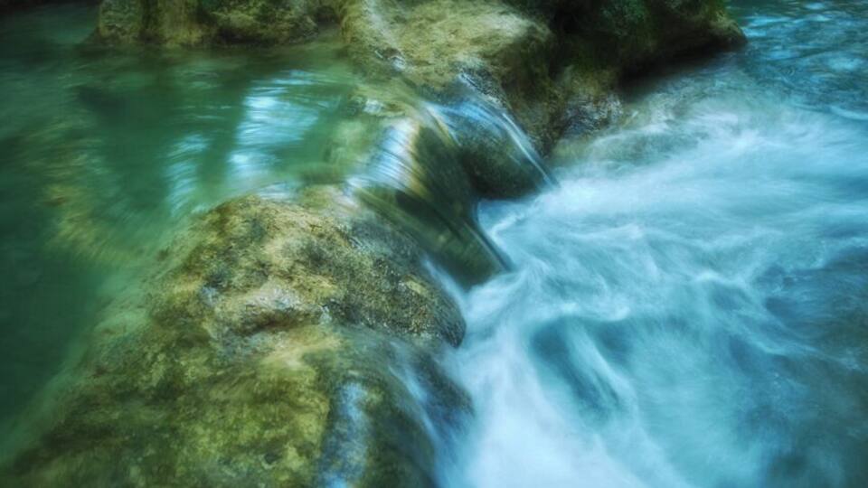 A flowing river with clear water and rocks.