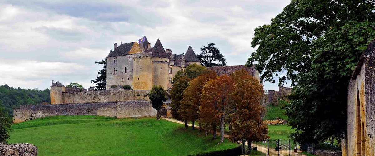 A historic castle on a hill with a paved road leading to it.