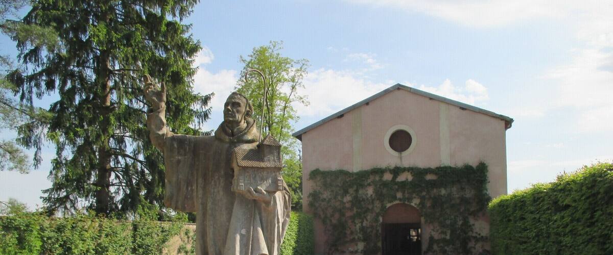 A statue of a man in a garden with a building in the background.