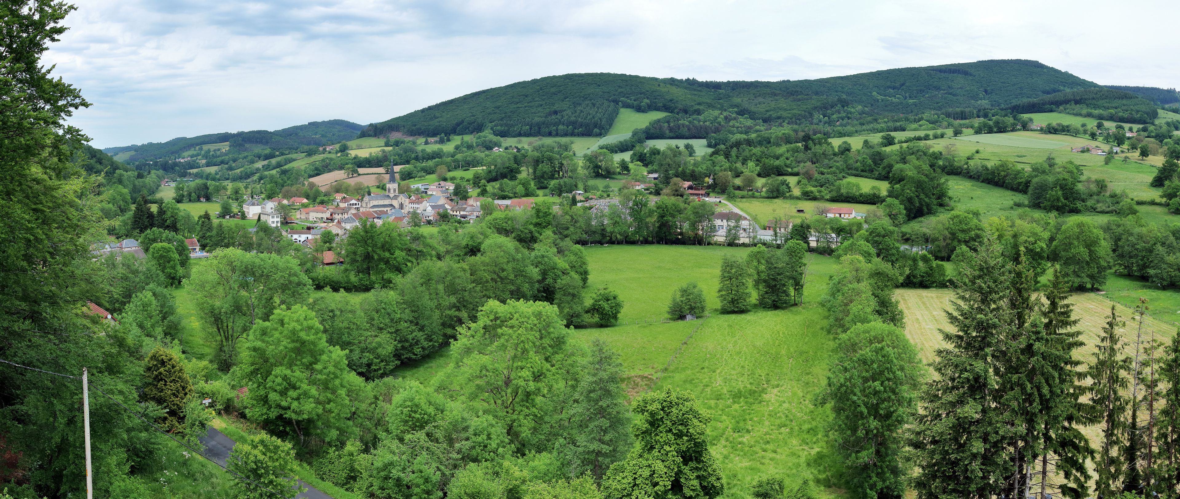 A village nestled in a valley surrounded by lush green hills and a prominent church.