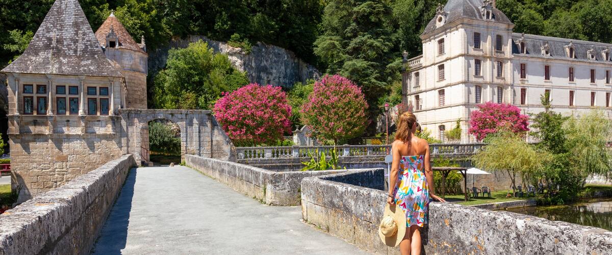 A stone bridge with pink flowering trees, a castle, and a tower.