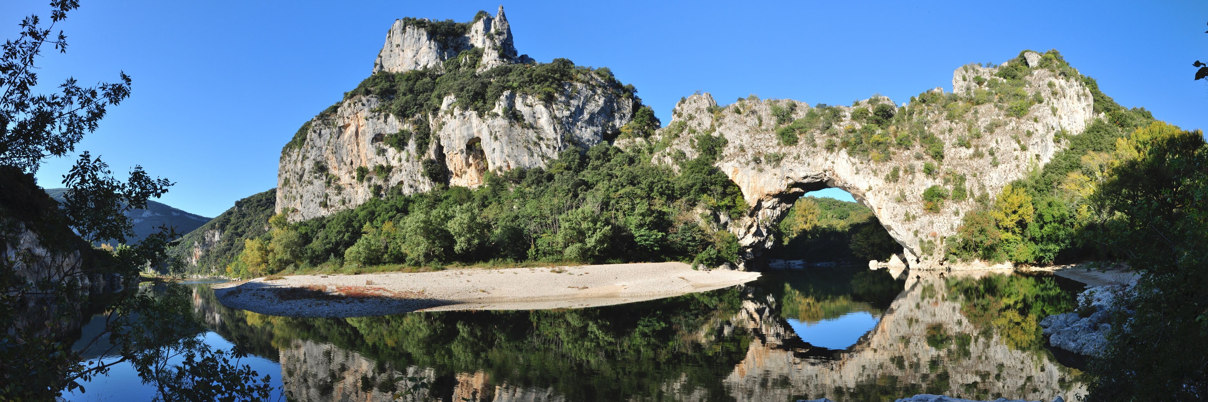 A lake with a rocky cliff and a cave-like structure.