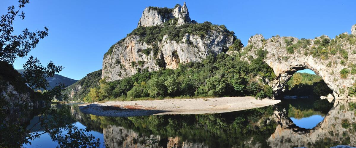 A lake with a rocky cliff and a cave-like structure.