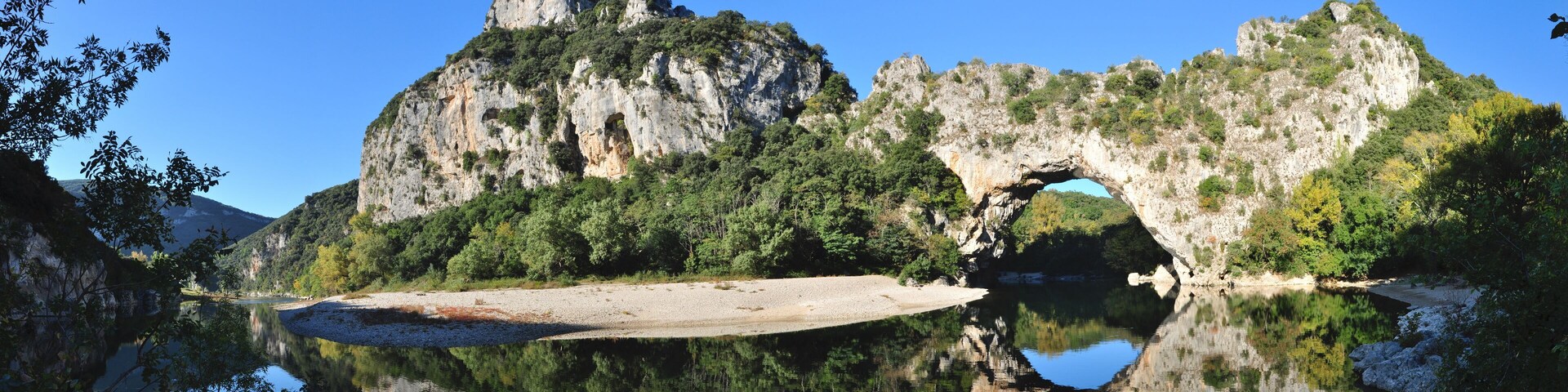 A lake with a rocky cliff and a cave-like structure.