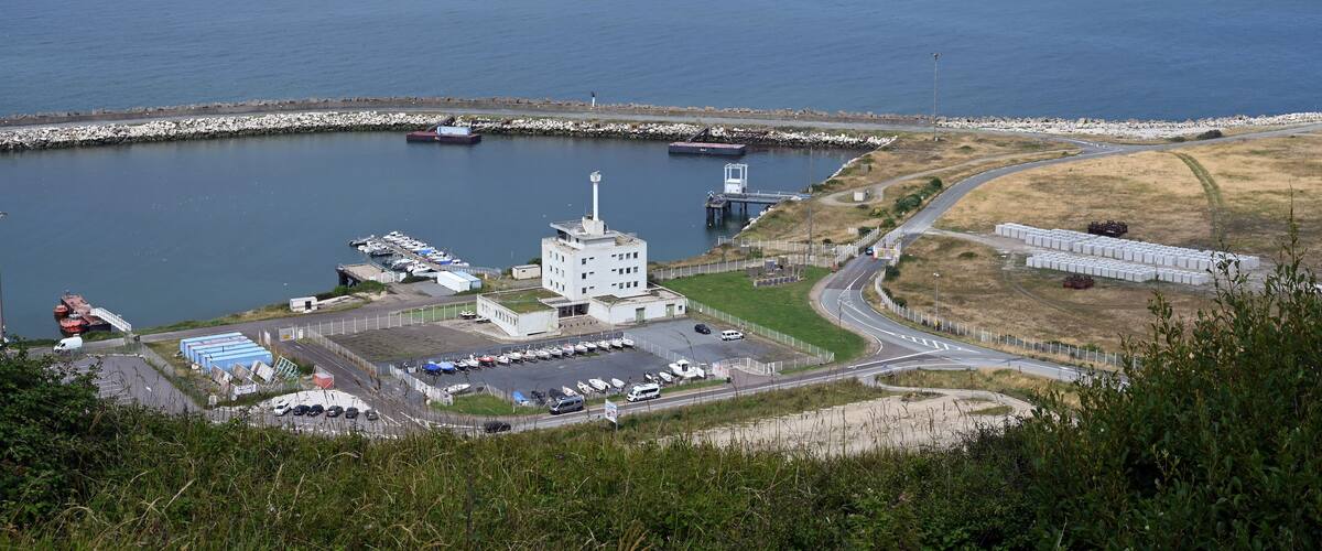 A coastal industrial area with a large body of water, a pier, and a power plant.