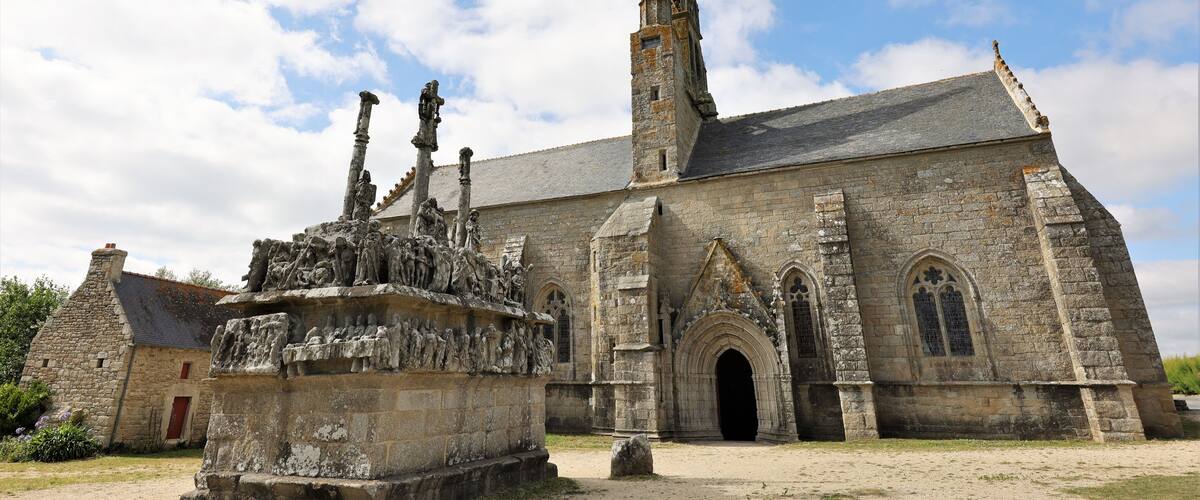 A historic stone church with a tall spire and a detailed stone sculpture in front.