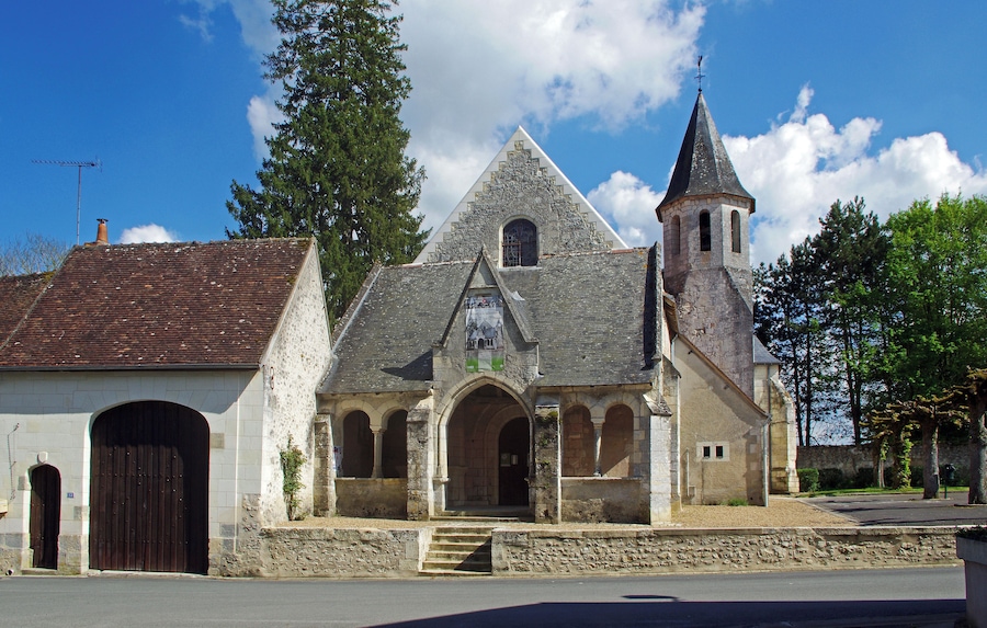 Una iglesia histórica con fachada de piedra, un campanario y una entrada arqueada grande.
