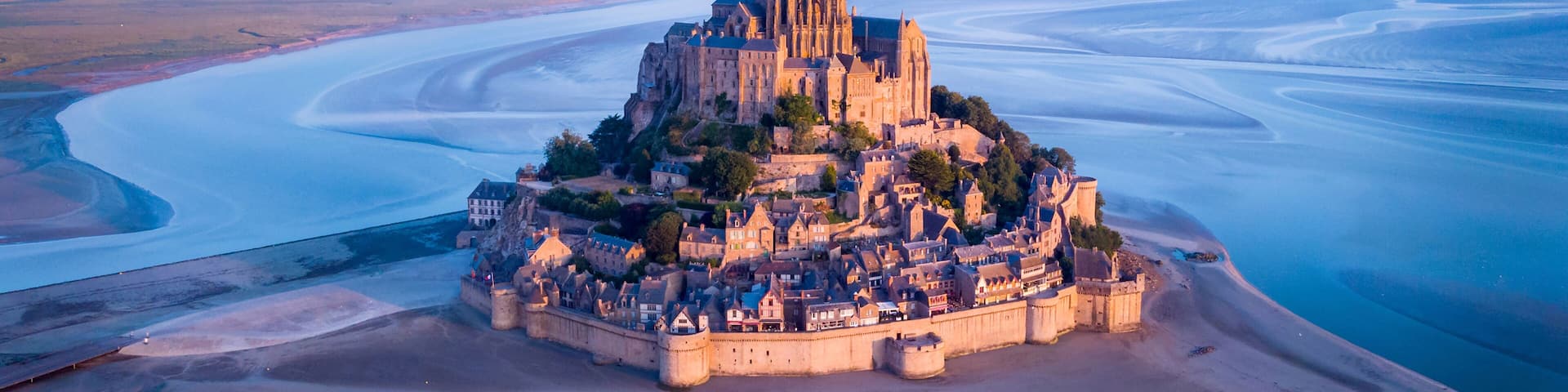 Aerial view of Mont Saint-Michel by river against sky during sunset