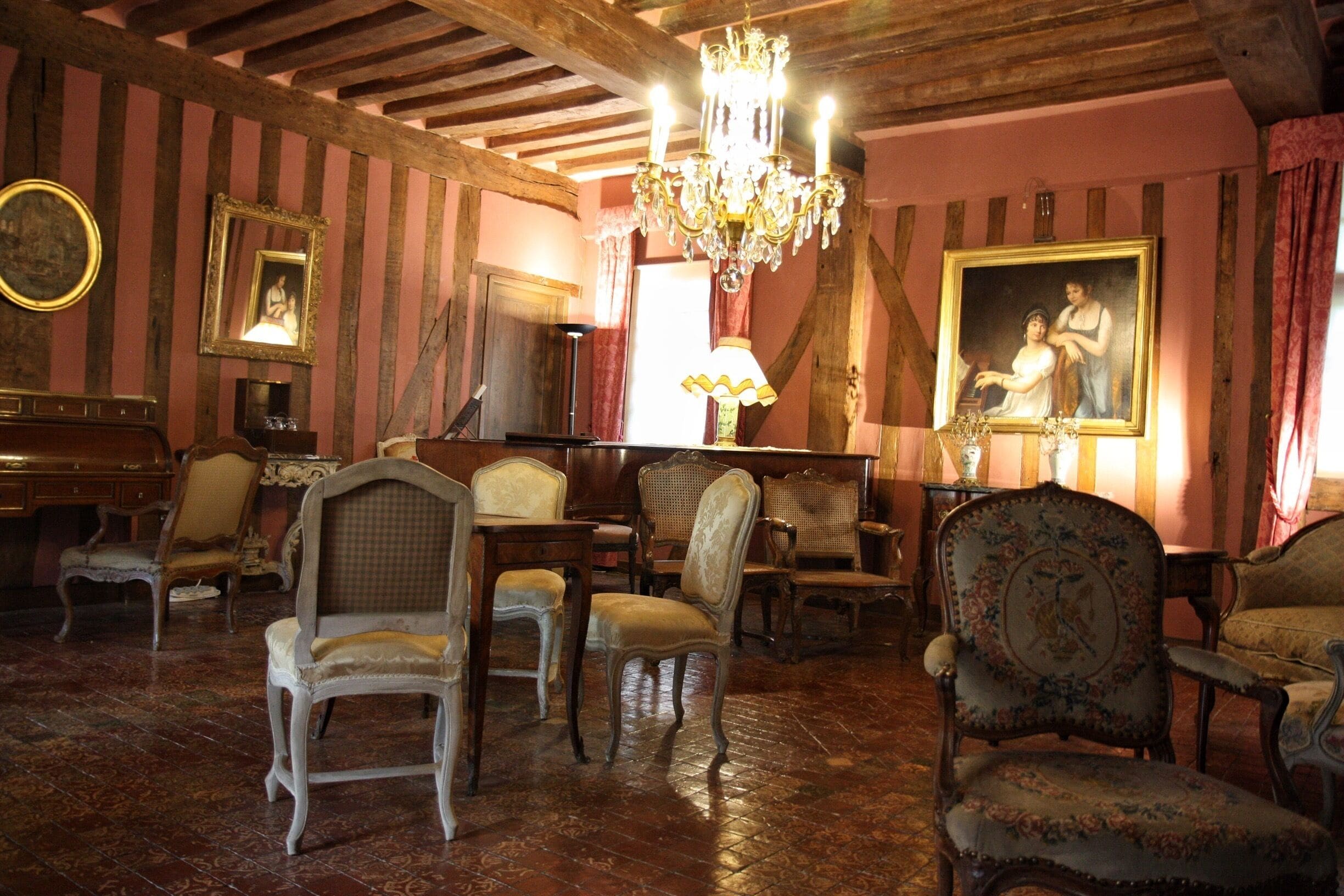 A room with antique furniture, a chandelier, and a large painting on the wall.