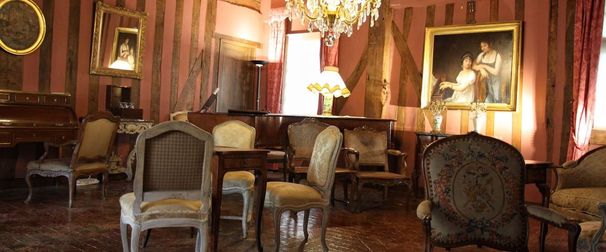 A room with antique furniture, a chandelier, and a large painting on the wall.