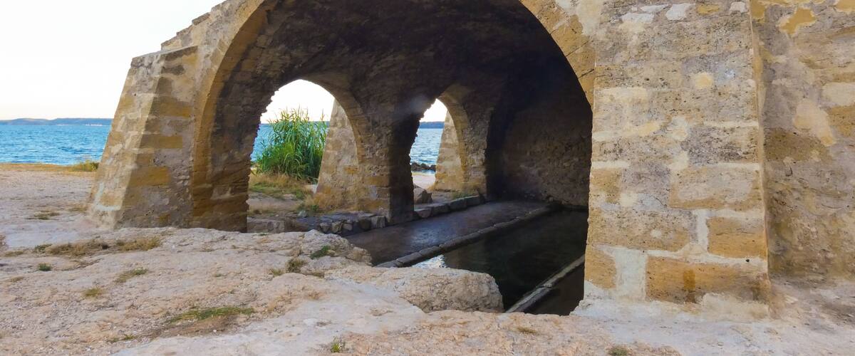 An ancient stone bridge with three arches over a body of water.