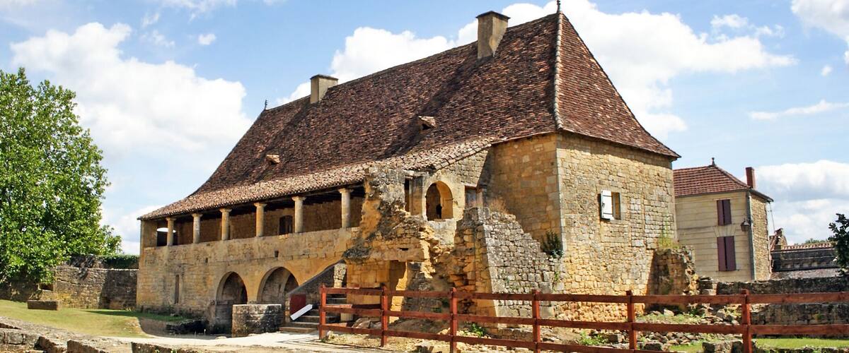 A historic stone building with a tiled roof and arched windows.