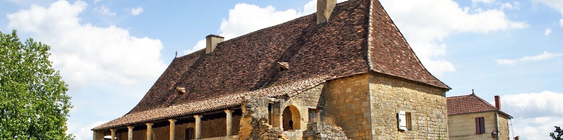 A historic stone building with a tiled roof and arched windows.