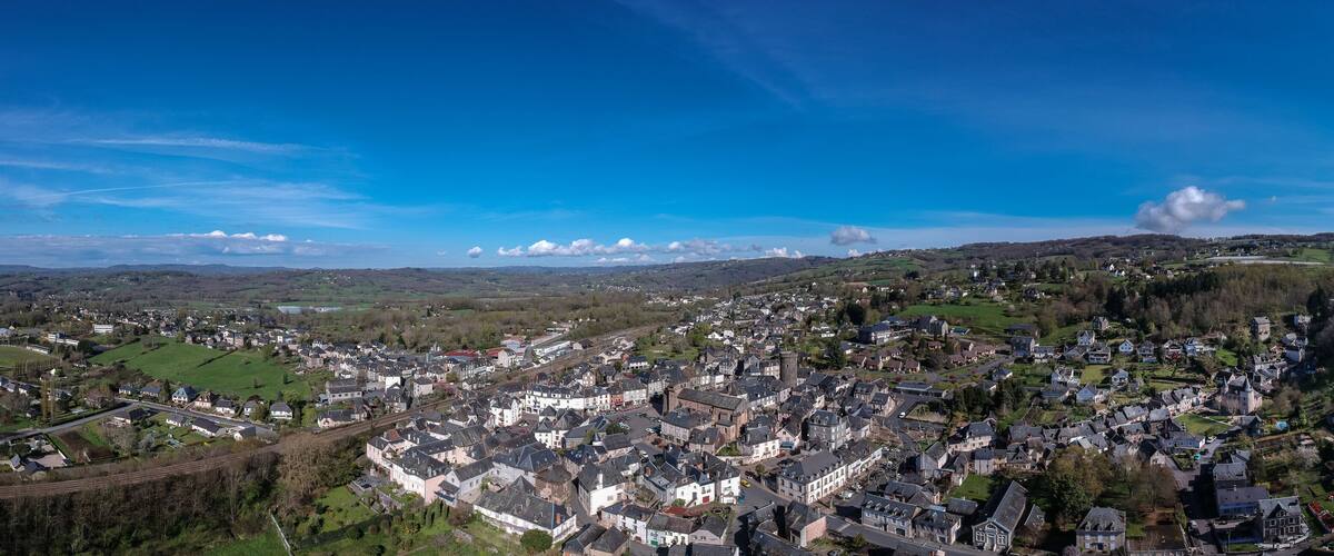 A panoramic view of a town nestled in a valley with rolling hills in the background.