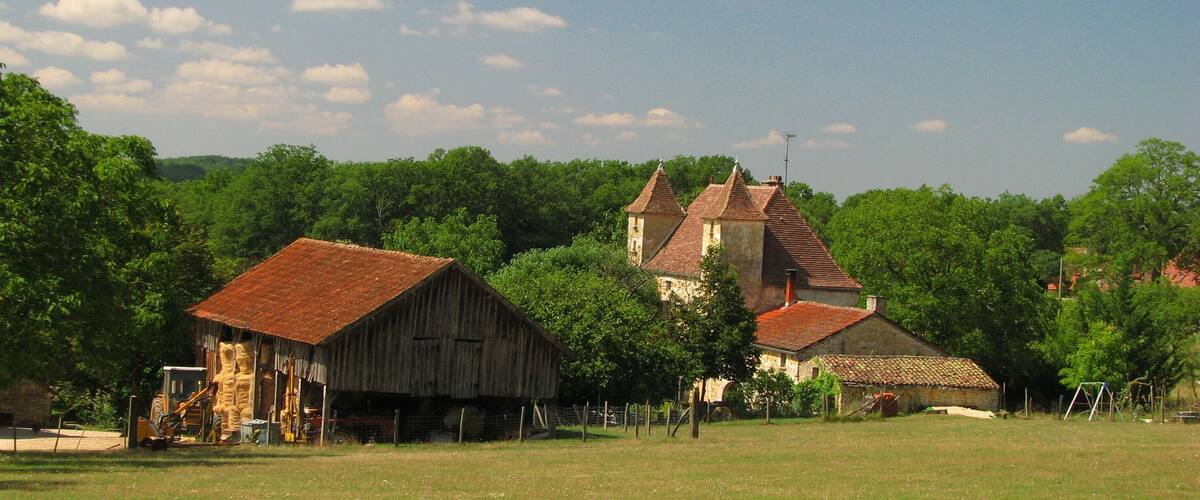 A rural landscape with a barn, a church, and lush greenery.