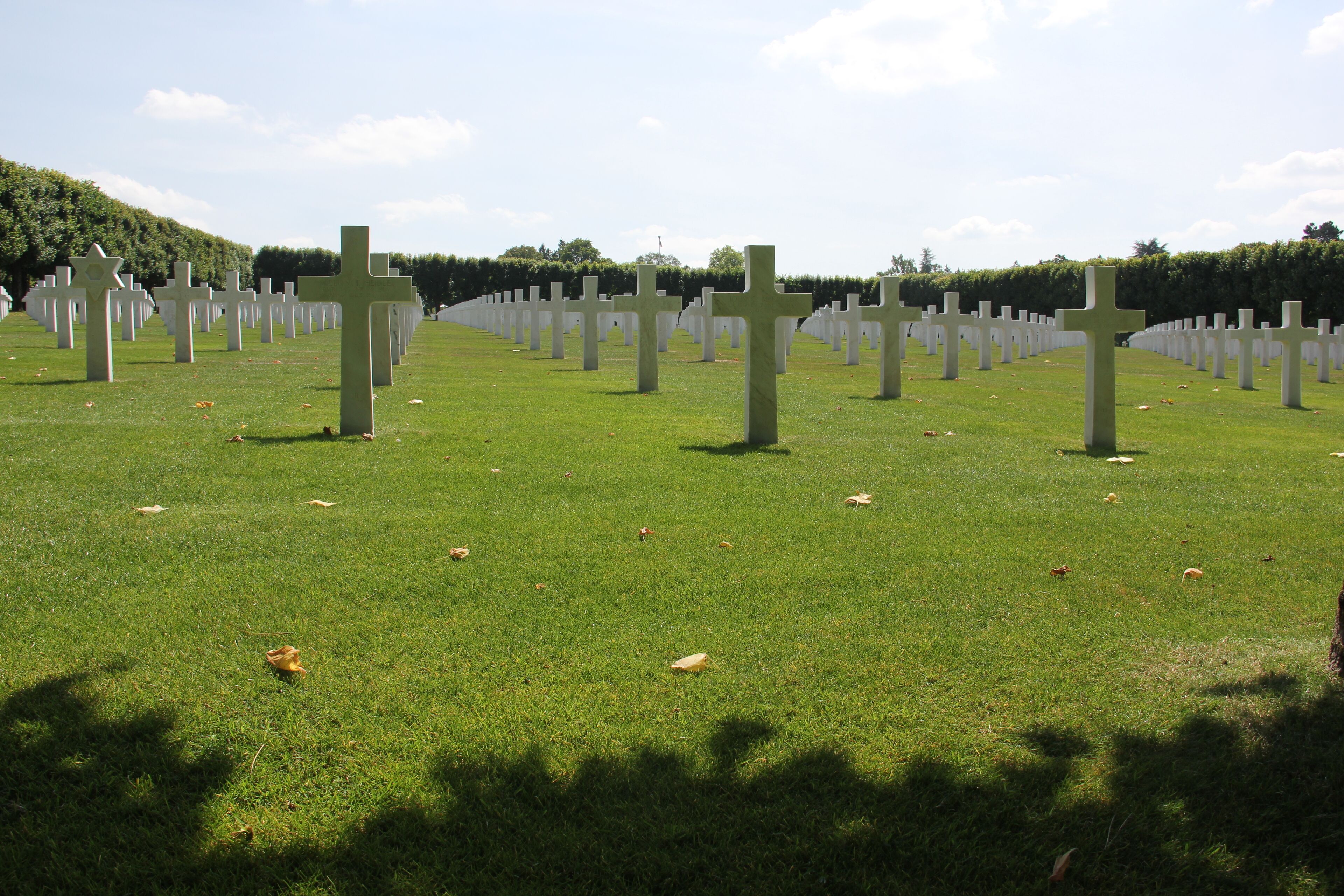 A cemetery with numerous white crosses arranged in rows on a grassy field.