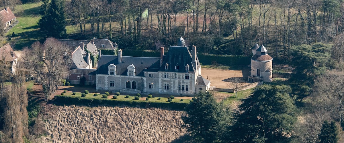 A large stately manor with multiple towers and a well-manicured garden.