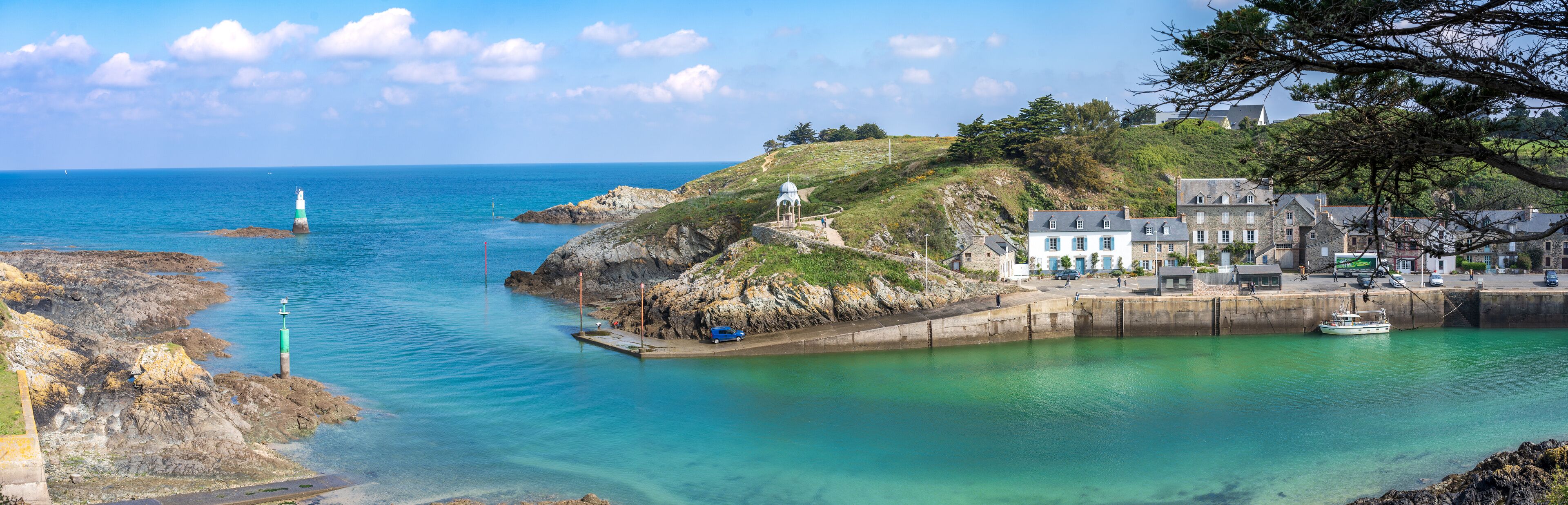 A coastal town with a lighthouse, rocky shoreline, and a harbor with boats.