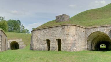 A stone building with a grassy roof and arched doorways.