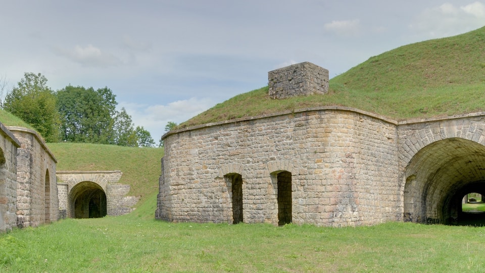 A stone building with a grassy roof and arched doorways.