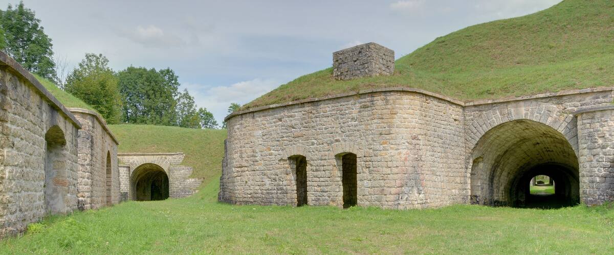 A stone building with a grassy roof and arched doorways.