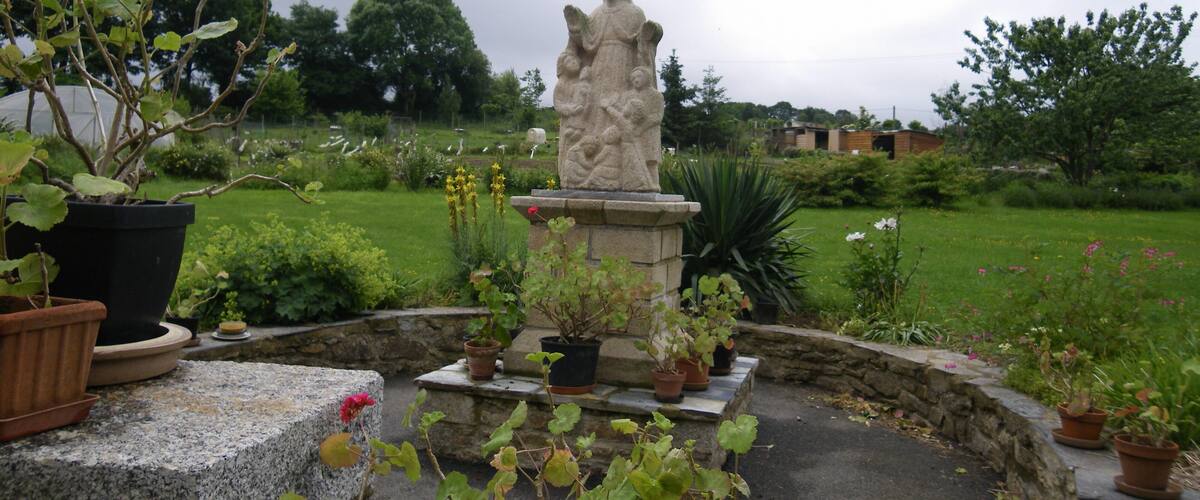 A garden with a statue, potted plants, and a grassy field.