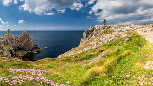 Un paysage côtier avec des falaises rocheuses, un ciel dégagé et une vue lointaine sur la mer.