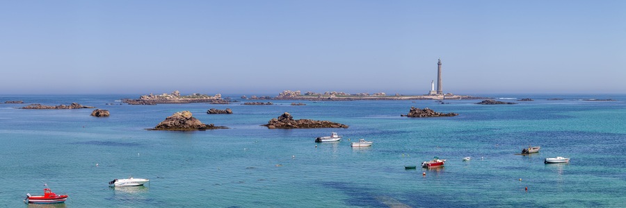 A coastal scene with a lighthouse, rocky outcrops, and several boats.