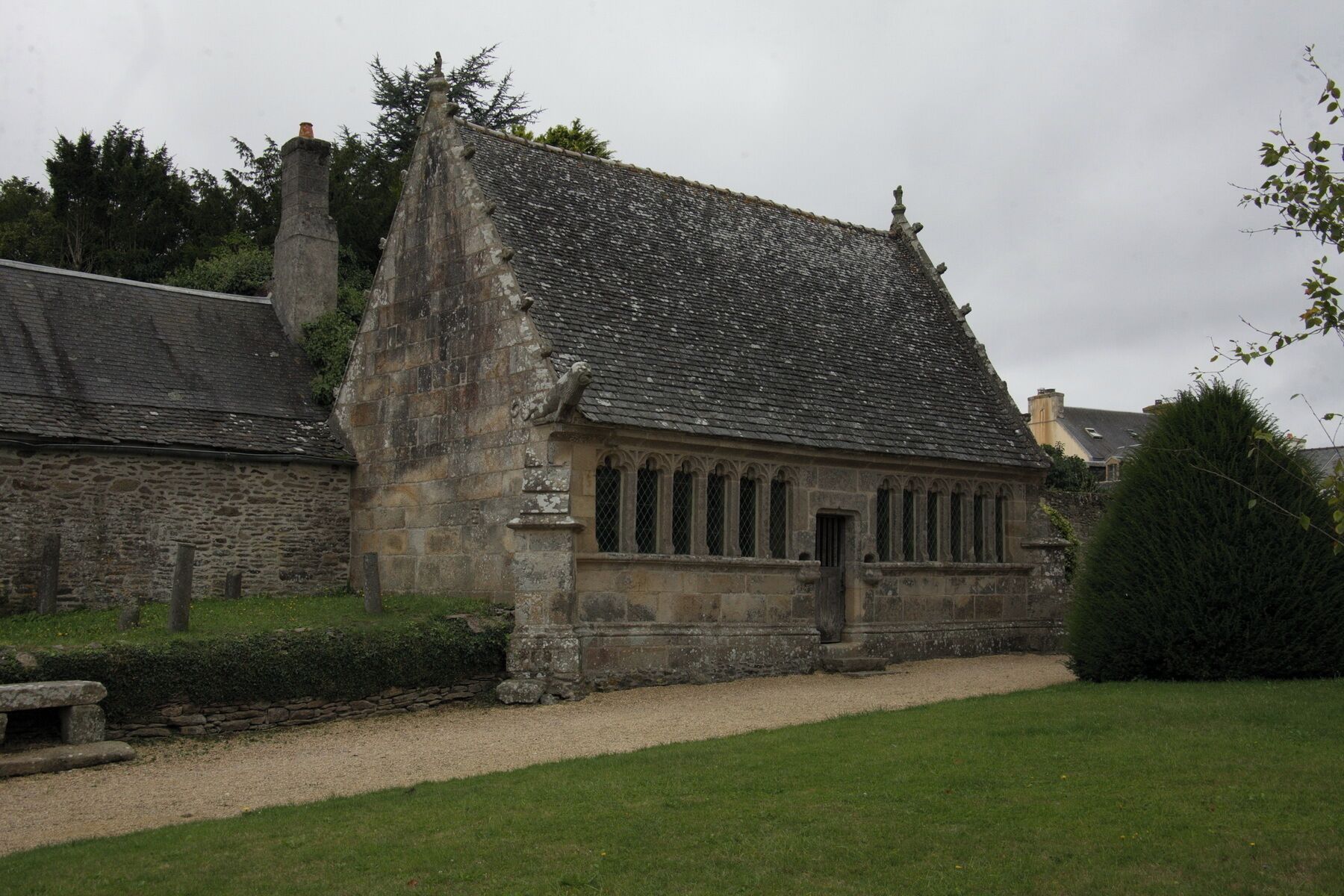 A stone building with a steeply pitched roof, a stone chimney, and a small door.