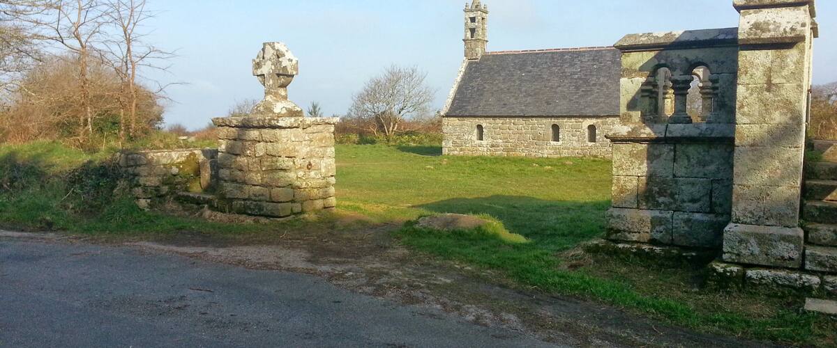 A stone church with a bell tower and a grassy field in the foreground.
