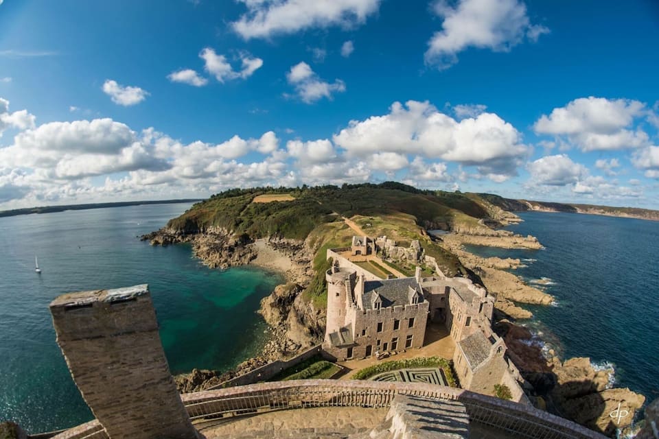 A coastal castle with a clear view of the surrounding cliffs and the sea.