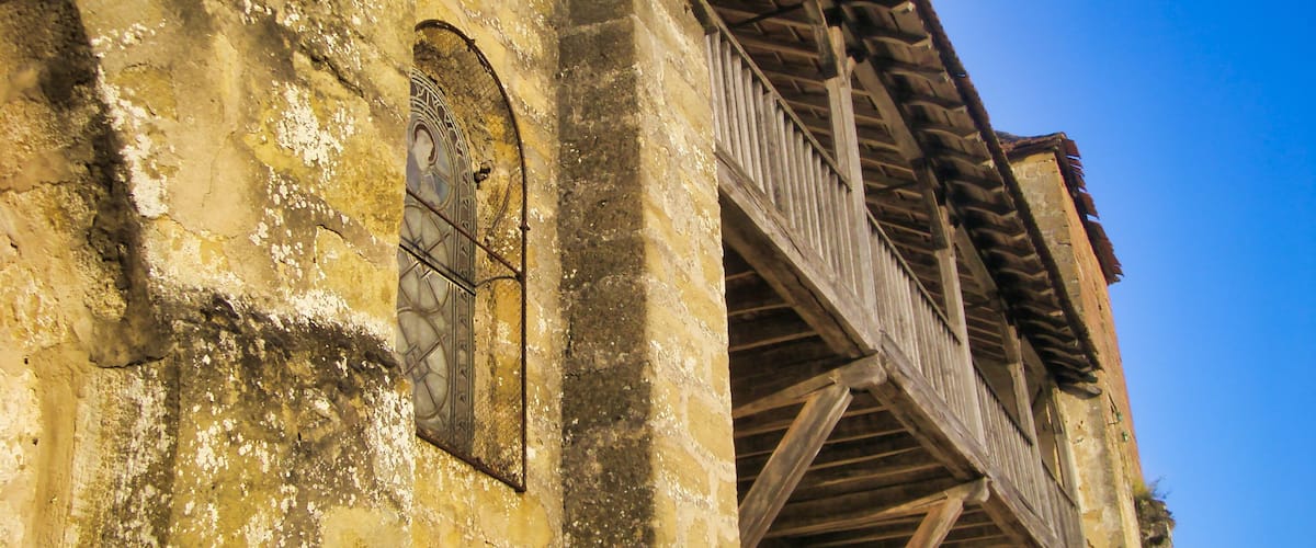 An old building with weathered walls and a wooden balcony.