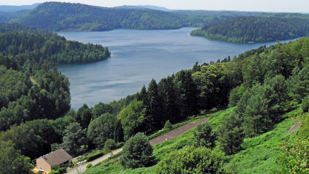 A lake surrounded by dense forest and hills.