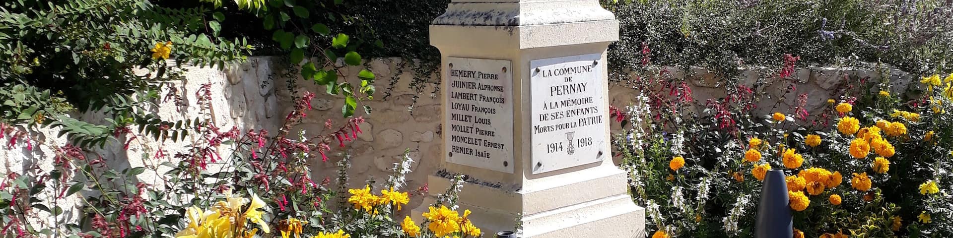 A memorial monument surrounded by colorful flowers and greenery.