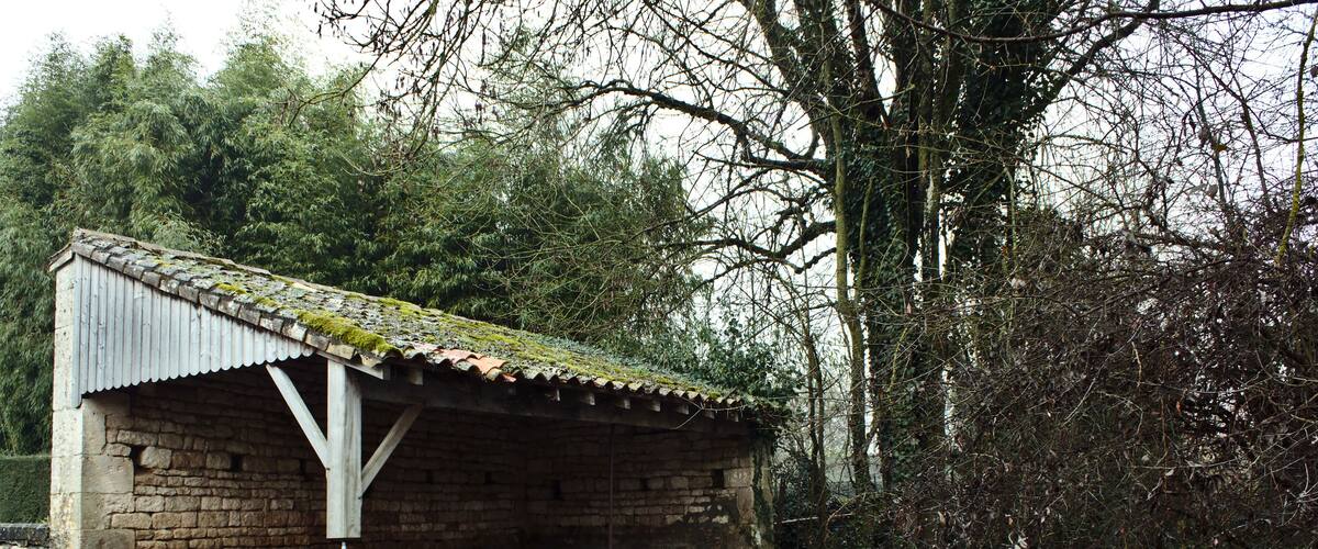A stone bridge over a flowing stream with a small wooden shelter on the left.