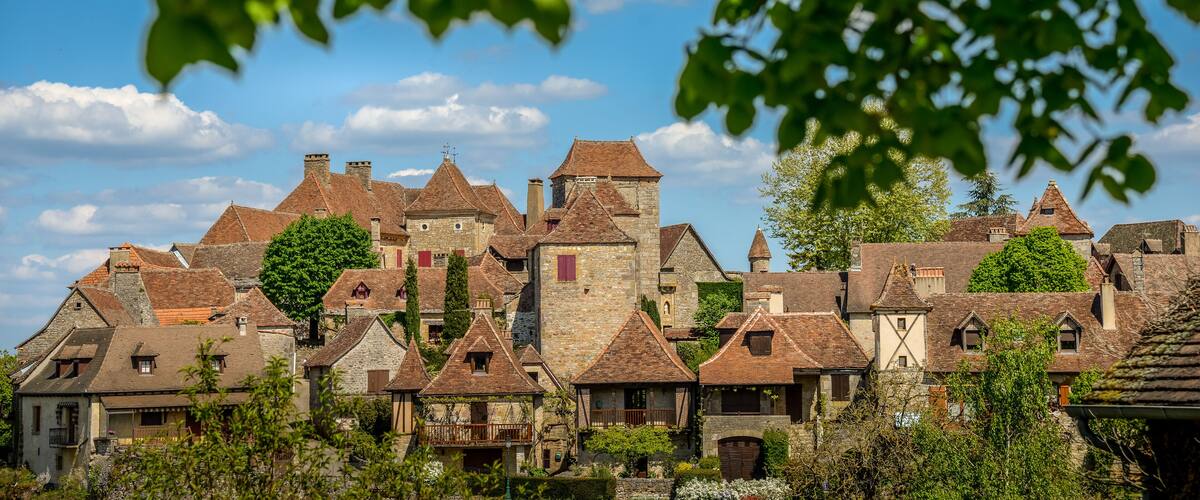 A historic village with stone buildings, red-tiled roofs, and a prominent tower.