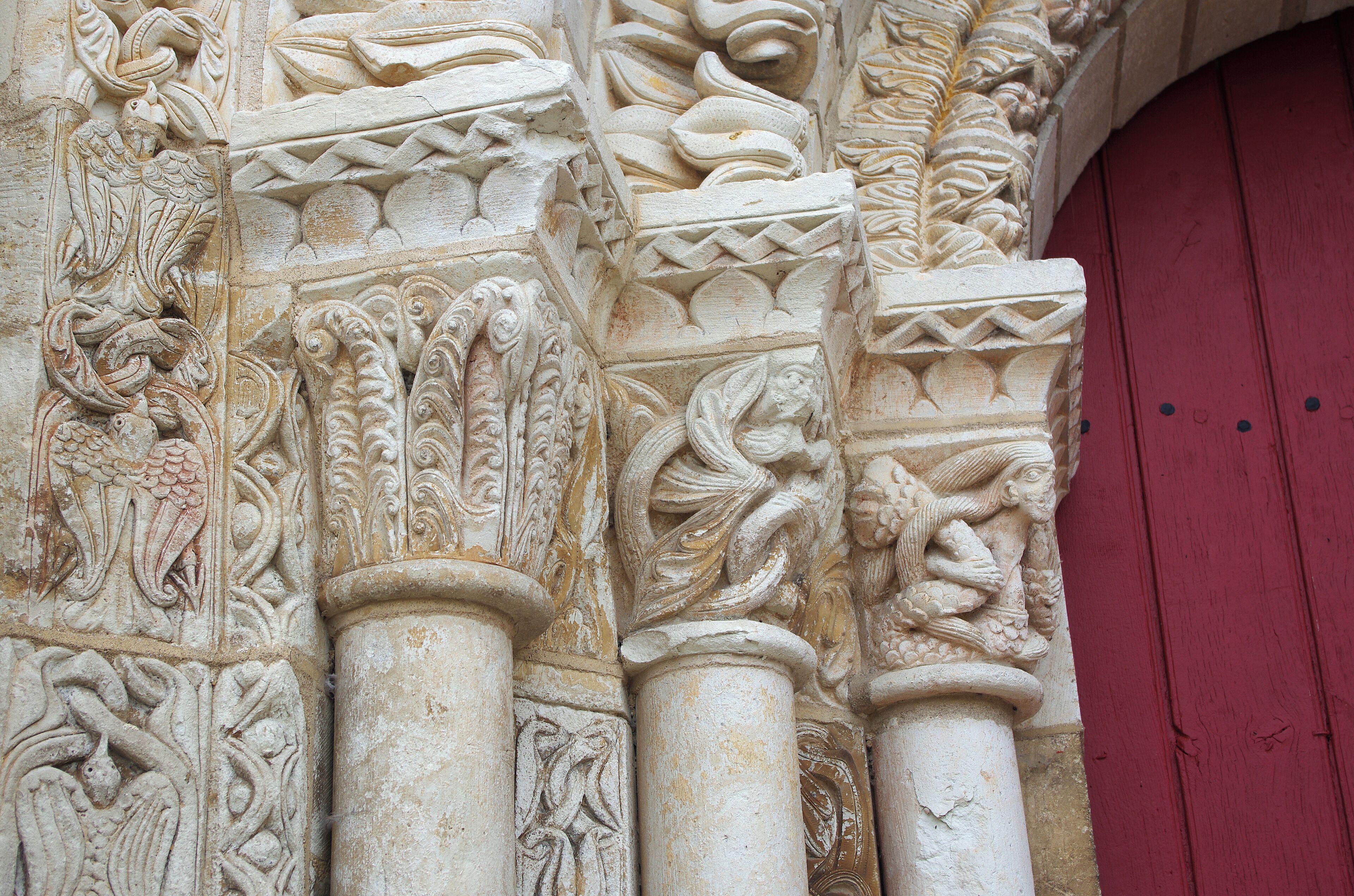 Detailed stone carvings on a column with a red door in the background.