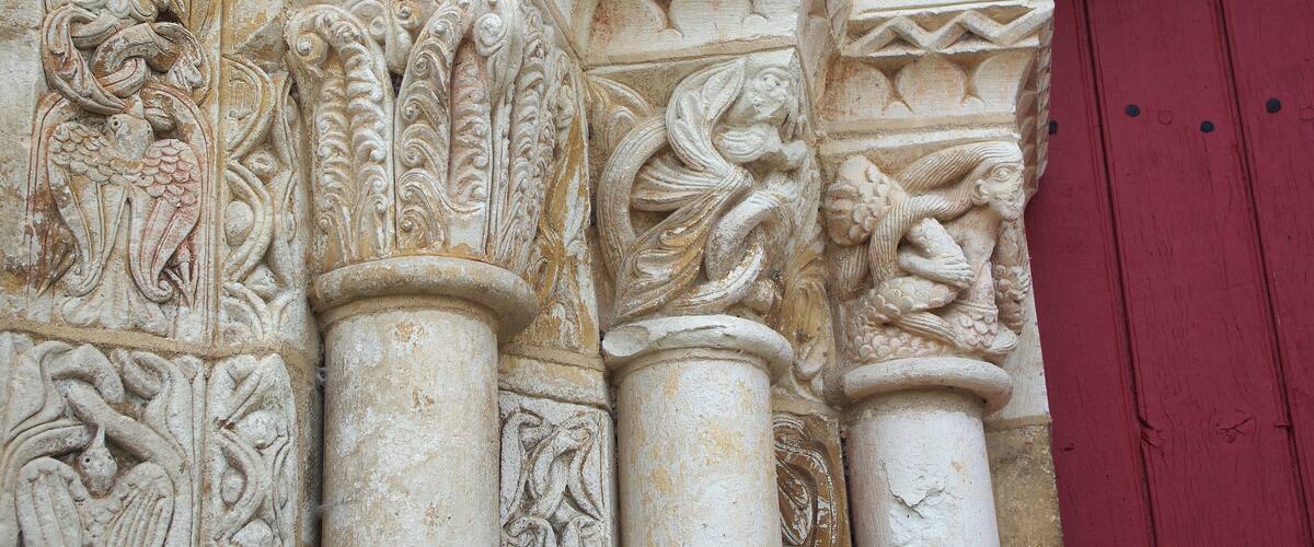 Detailed stone carvings on a column with a red door in the background.