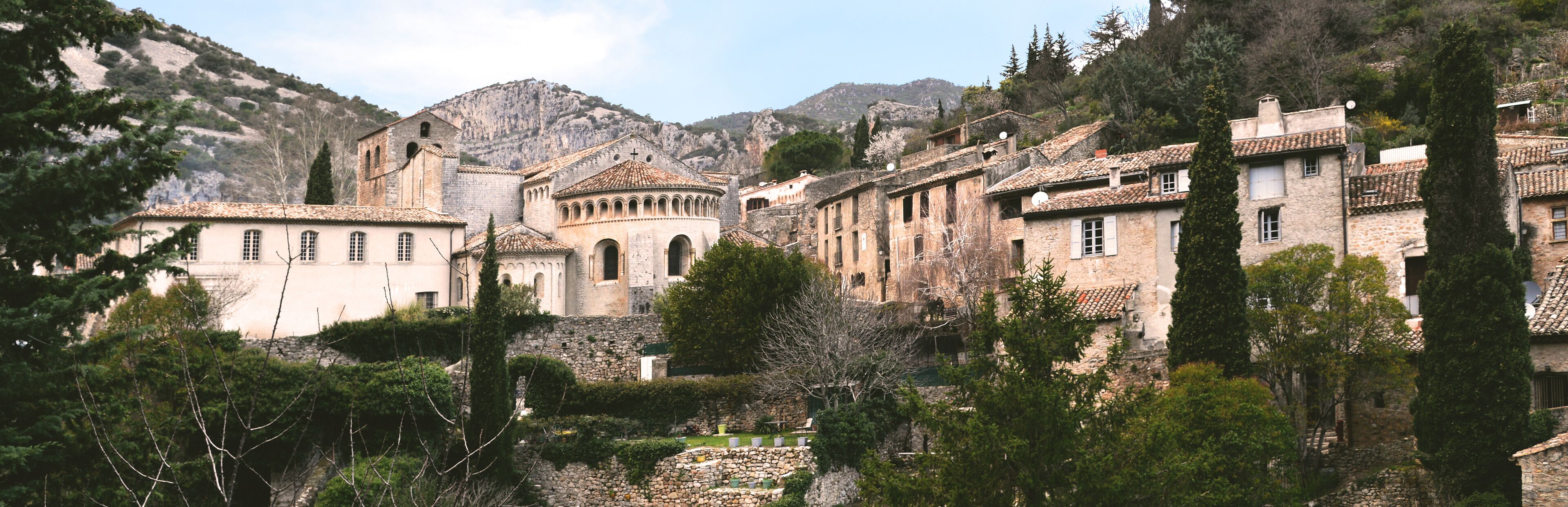 A historic town with stone buildings, a prominent church, and a mountainous backdrop.