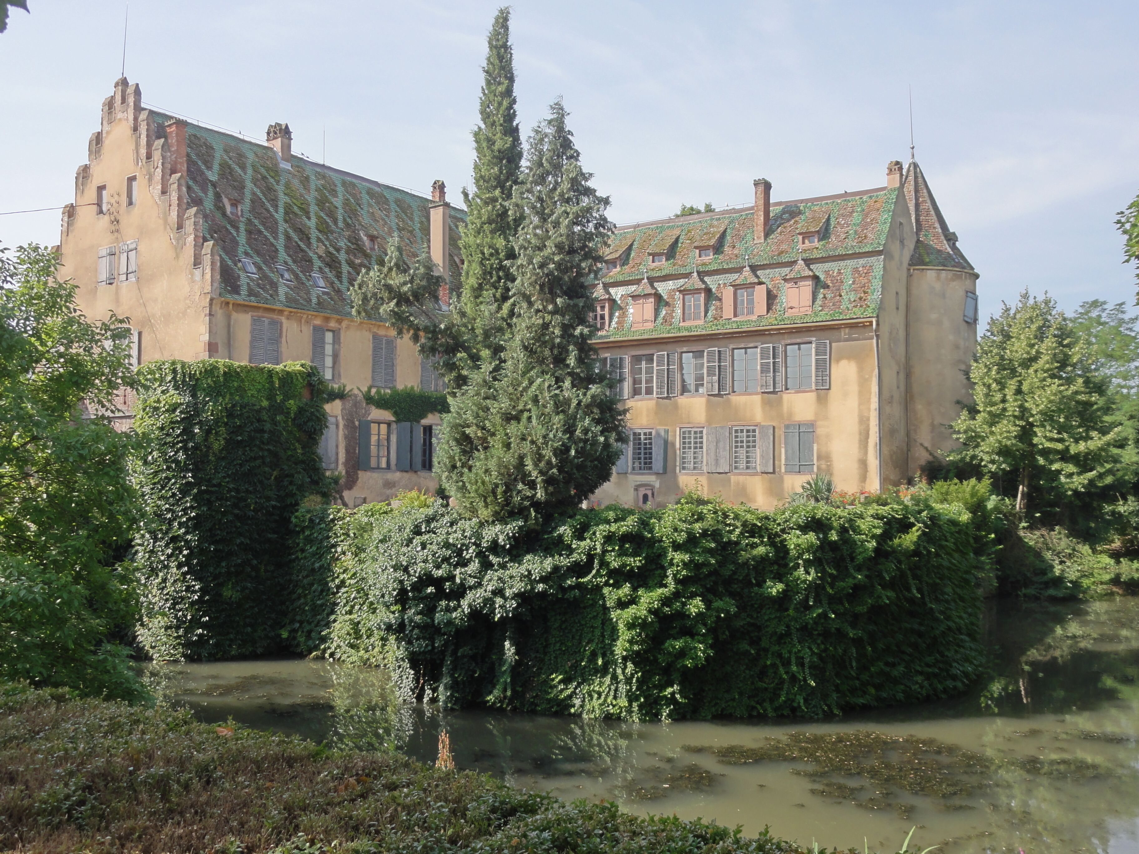 A large, historic building with a green roof and ivy-covered walls.