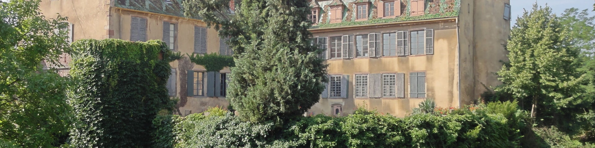 A large, historic building with a green roof and ivy-covered walls.