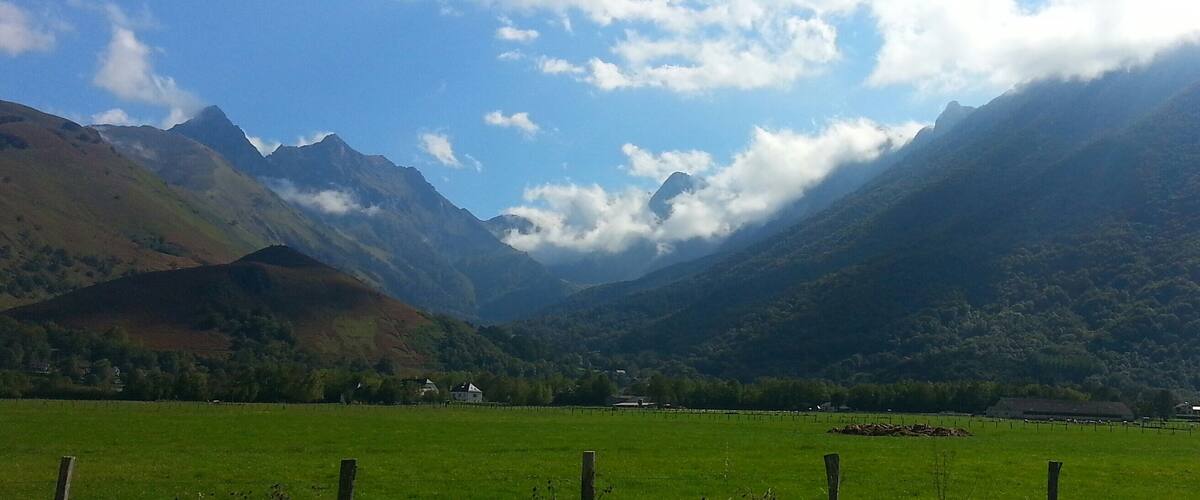 A valley with mountains, a clear sky, and a green field.