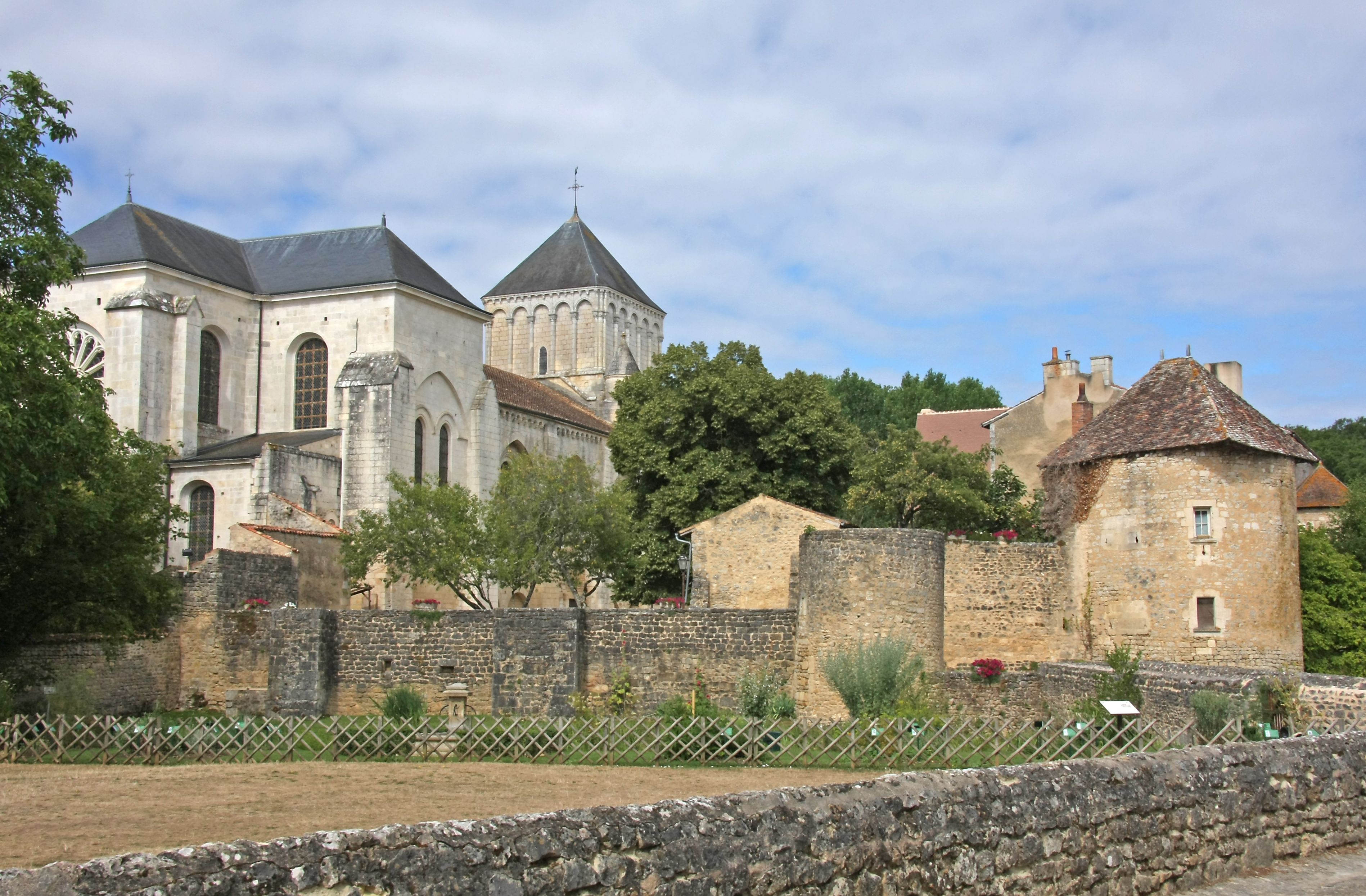 A historic church with a bell tower and a stone wall with a fence in the foreground.