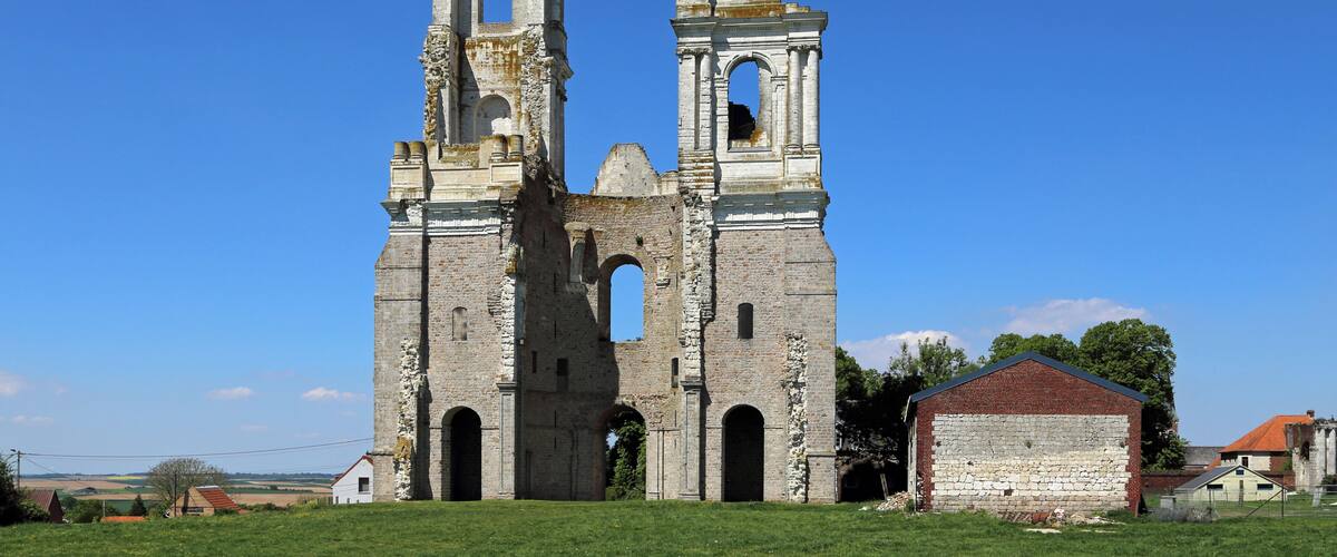 A large, historic stone church with two bell towers and a small brick building in the foreground.