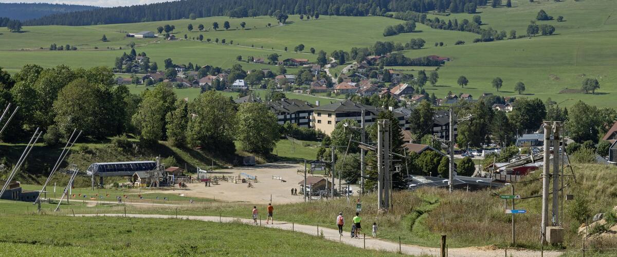 A rural landscape with rolling hills, a small village, and a sports field.
